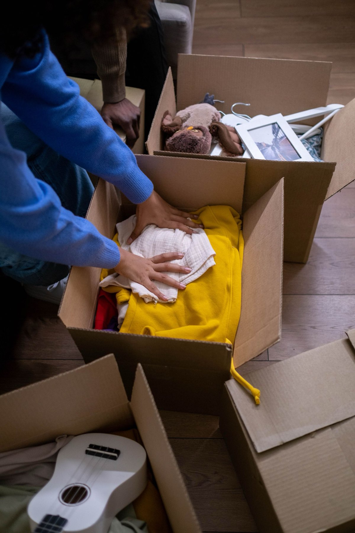 Hands packing clothes into a cardboard shipping box